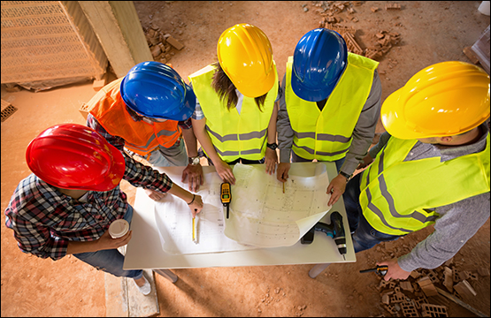 Overhead picture of workers looking down onto construction drawings